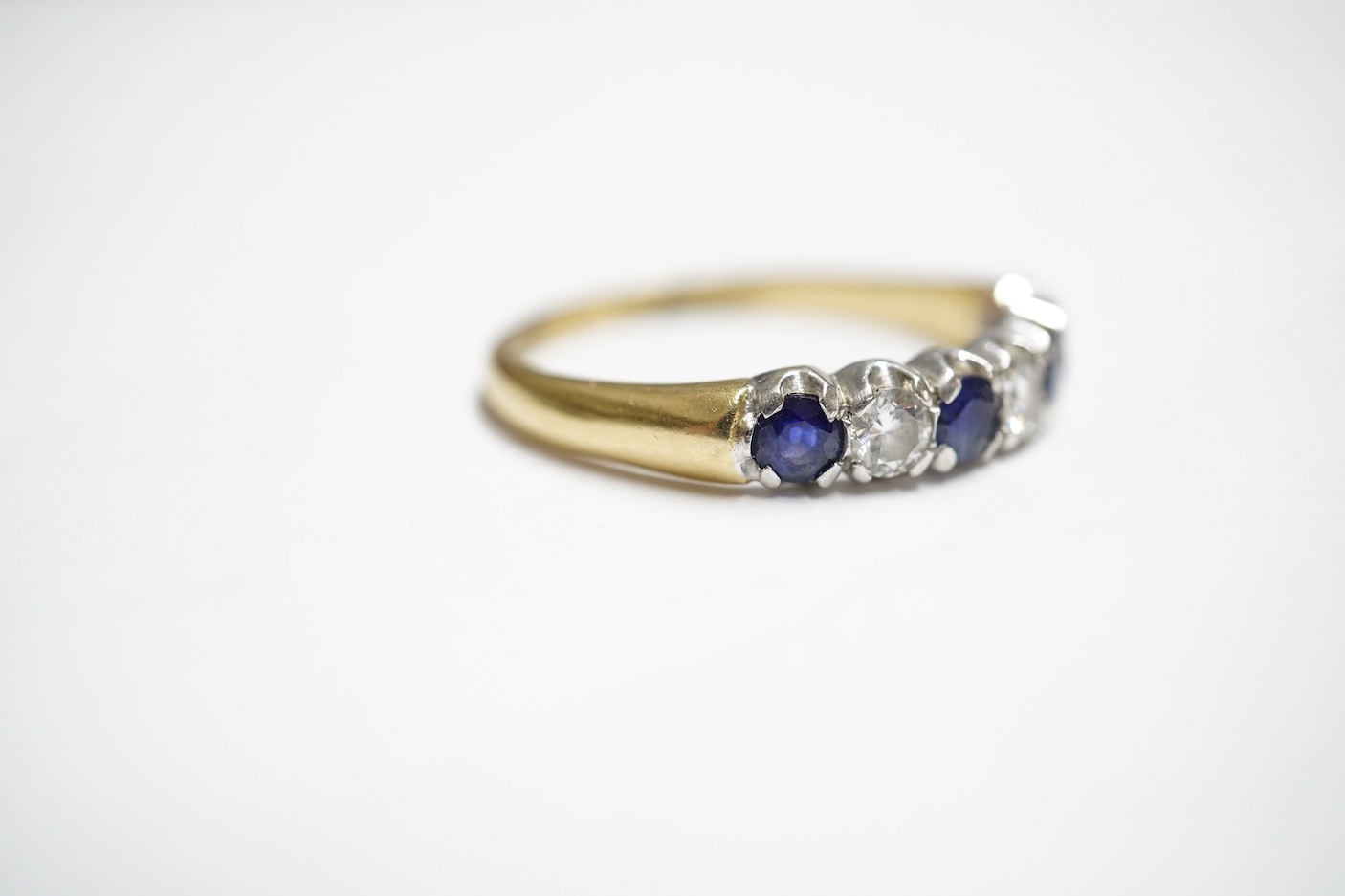 A sapphire and diamond ring, set with an alternating sequence of brilliant-cut diamonds totalling approximately 0.45 carats, and circular-cut sapphires, in 18ct gold, size Z+, British hallmarks, gross weight approximatel